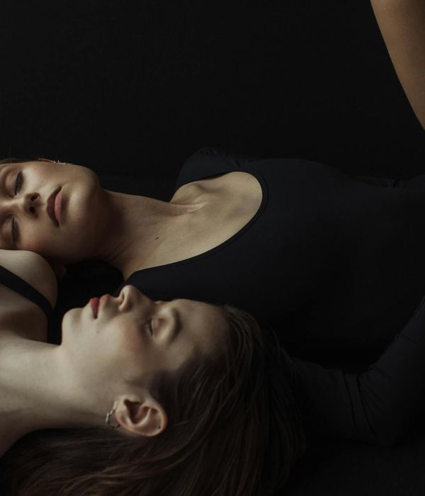 Woman performing a calm yoga pose in a dark, elegant setting.